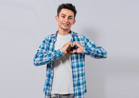Smiling guy making heart shape with hands isolated. Happy man making heart shape with hands