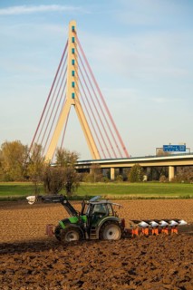 Farmer ploughing a field, tractor with plough, near Neuss, Fleher motorway bridge, A46, North