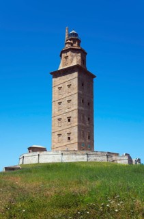 Old lighthouse under a bright blue sky, surrounded by green landscape, Torre de Hércules, Torre de