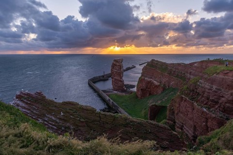 Red sandstone cliff with Lange Anna on the offshore island of Heligoland, pier as protection