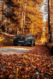 Car on autumnal forest road with orange leaves, electric car VW ID5, Gechingen, Black Forest,