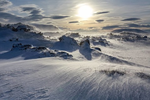 Solidified lava and stones in a snowstorm, windy, sunny, backlight, Myvatn, Iceland, Europe