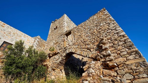Weathered stone wall of a fortress with arches and surrounding vegetation, Vathia, residential