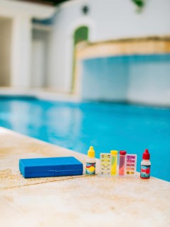 Chlorine and ph tester for swimming pools. Water test kit on the edge of the swimming pool.