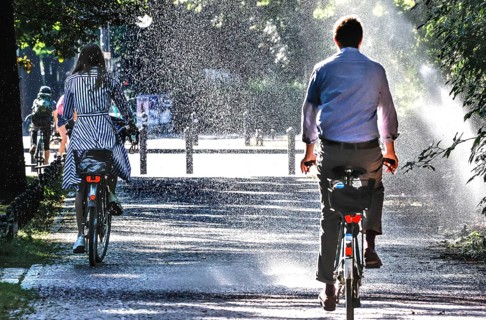 A cyclist cools down with a lawn sprinkler in Berlin's Tiergarten, 03/08/2022
