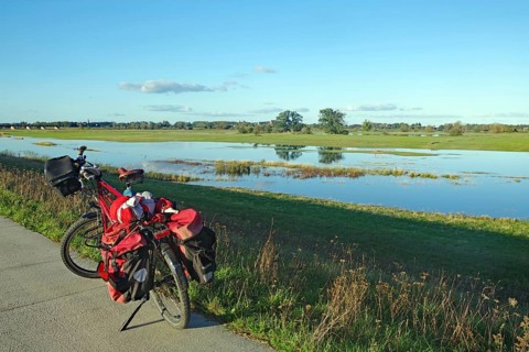 A bicycle stands at the edge of a dyke path next to a flooded Elbe meadow in a wide meadow