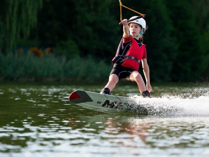 Boy or girl with wakeboard in the lake, water sports, water skiing in the wake park