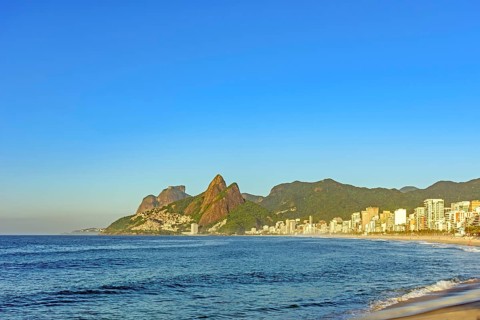 Ipanema Beach in the city of Rio de Janeiro at sunrise with the sea, buildings and mountains, Rio