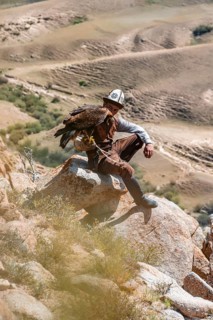 Traditional Kyrgyz eagle hunter hunting in the mountains in a dry landscape, near Kysyl-Suu, Issyk