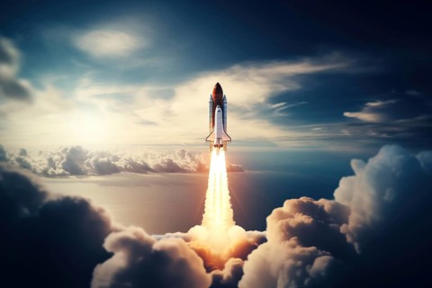 Aerial view of a rocket shuttle carrier launch at sunrise over an ocean coast. The rocket is