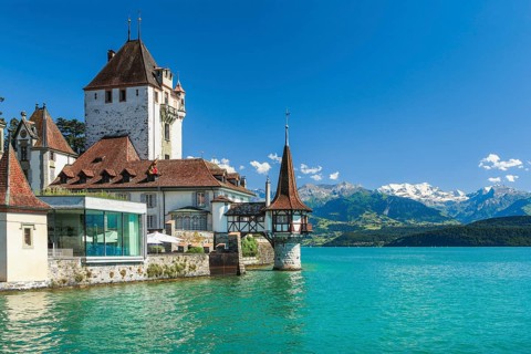 Oberhofen Castle on Lake Thun with a view of the mountains with the snow-covered Blüemlisalp,