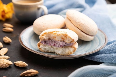 Meringues cakes with cup of coffee on a black concrete background and blue linen textile. Side