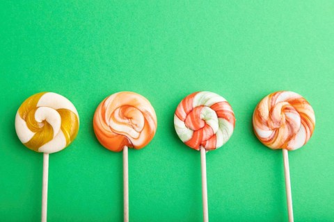 Four lollipop candies on green pastel background. copy space, top view, flat lay
