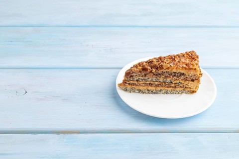 Walnut and hazelnut cake with caramel cream on blue wooden background. side view, copy space