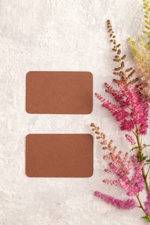 Brown paper business card mockup with purple astilbe flowers on gray concrete background. Blank,