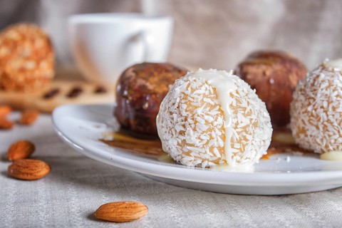 Energy balls cakes with chocolate caramel and coconut on white plate on linen napkin, selective