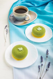 Green mousse cake with pistachio cream and a cup of coffee on a white wooden background and blue