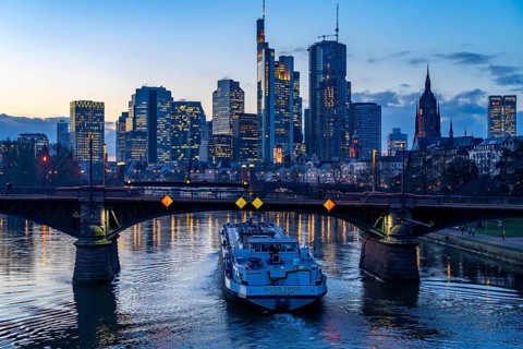 Skyline of the city centre of Frankfurt am Main, river Main, dusk, Ignatz-Bubis-Bridge, cargo ship,