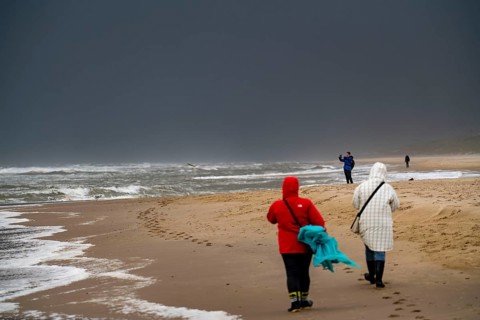 Walkers on the beach, dark storm clouds, choppy sea, autumn on the North Sea in North Holland,