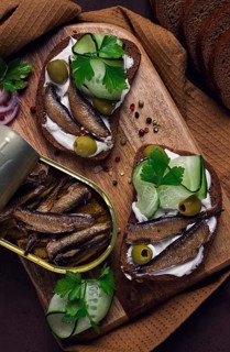Sandwiches, black bread with sprats, cream cheese, cucumbers, on a cutting board, top view,