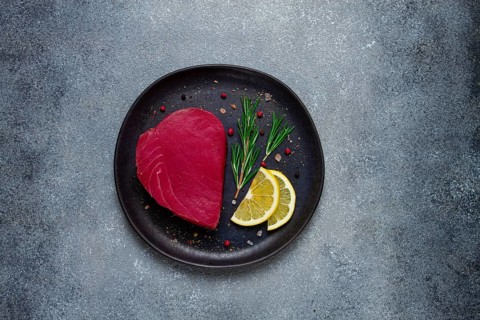 Fresh red tuna fillet, for steak, raw, top view, on a black plate, no people