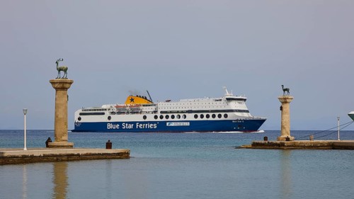 Ferry boat sailing between columns with statues on blue sea, Deer statue, Deer statue, Mandraki