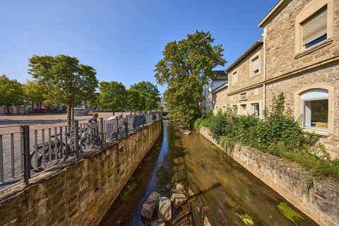 River Salze with historic buildings at the Salzhof square under a blue cloudless sky in the city