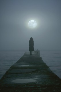 Silhouette of a lonely, sad woman on a concrete footbridge on a foggy full moon night, symbolic
