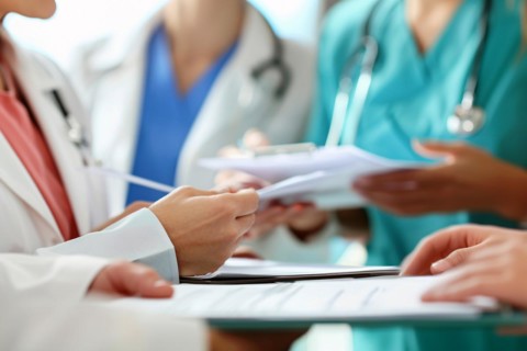 Staff meeting between doctors and nurses sharing documents in hospital or clinic. KI generiert,