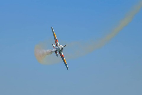 Stunt aerobatic plane performing stunts in blue sky with smoke trail. Concept of speed, difficulty,