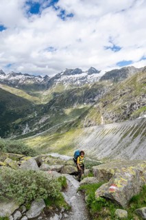 Mountaineer on a hiking trail in front of a picturesque mountain landscape, rocky mountain peaks