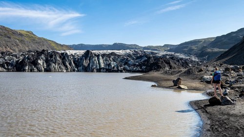 Tourist on the shore of a glacier lagoon, glacier tongue and lake, Sólheimajökull, South Iceland,