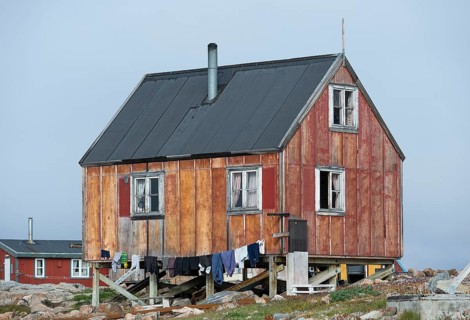Small red house, clothesline with hanging laundry, remote Arctic Inuit settlement Ittoqqortoormiit,