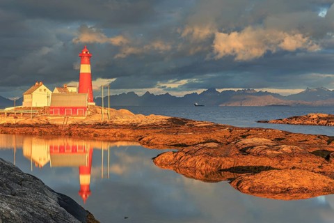 Lighthouse reflected in water, morning light, clouds, mountains, coast, Tranoy, Ofoten, Norway,