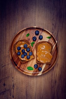 Rye bread with peanut paste and fresh blueberries, top view, no people