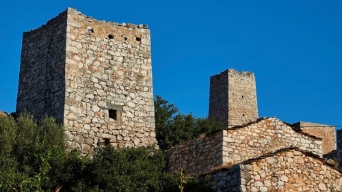 Ancient stone towers rise under a clear blue sky, Lagia, residential towers village, Mani