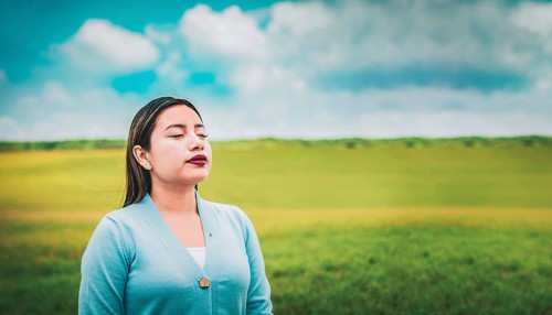 Close up of relaxed woman breathing fresh air in the field. Relaxed girl breathing fresh air in the