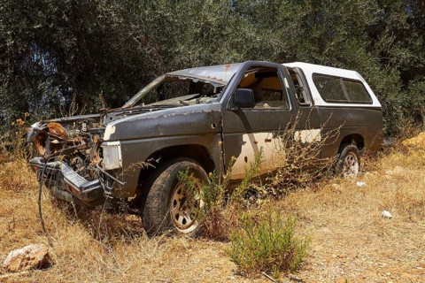 Abandoned rusted car with worn paint in a shady wooded area, wrecked vehicle, Crete, Greek Islands,