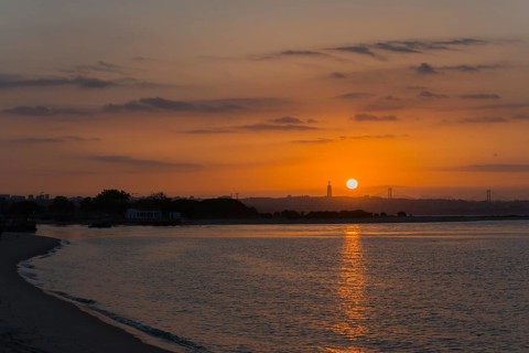 Peaceful coastal scene at sunset, the light reflects in the calm water while the sky glows in warm