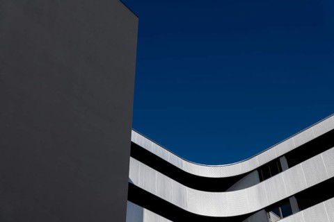 Beautiful Modern Concrete Design Building with Metal Balcony Against Blue Clear Sky in Switzerland