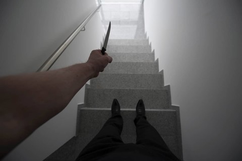 Personal Perspective on a Violent Man Holding a Knife in a Staircase with a Window Light in