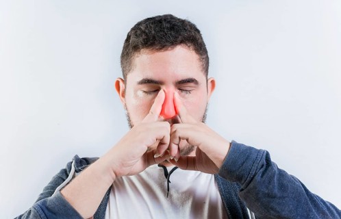 Sore person suffering with nasal bridge on isolated background. Suffering man with nasal congestion