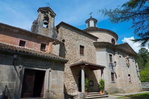 Stone church with bell tower and cross, surrounded by nature and under a blue sky, Santuario de San