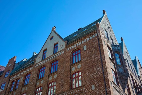 Row of historic Hanseatic houses with striking facades under a clear blue sky, Bryggen, Bergen,