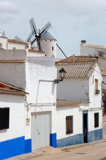 Small street with white and blue houses and a traditional windmill in the background, Campo de