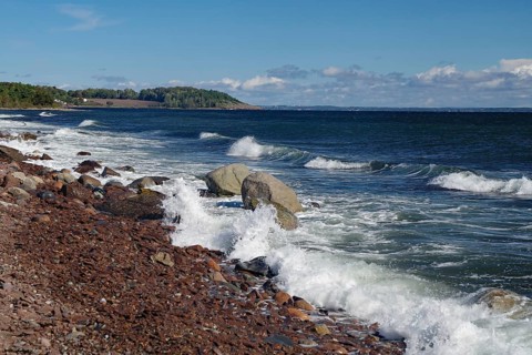 Rocks and waves meet a rocky coastline under a clear blue sky, Tönsberg, Oslofjord, Norway, Europe