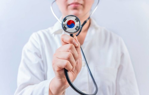 Female doctor holding stethoscope with South Korean flag. South Korean Health and Care concept