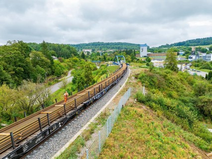 Train on railway line next to green countryside and city view, track construction, rail delivery