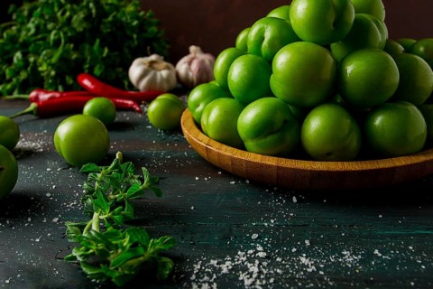 Tkemali, green cherry plum, with ingredients for sauce, cilantro, mint, hot pepper, garlic, on a