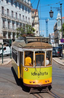 Yellow-green tram bends around a curve through the city, Tram, Line 28, Carros eléctricos de